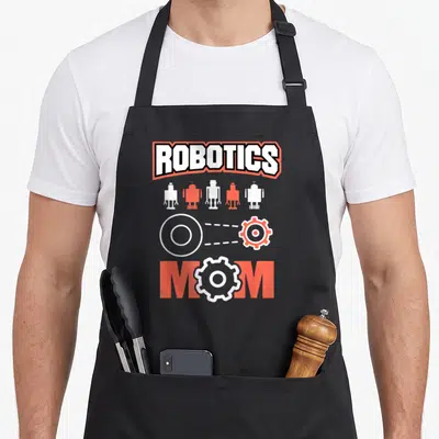 Robotic coding engineer apron - ROBOTICS and MOM text with five robots and gears in orange and white — shown on a black cotton canvas apron against a white background