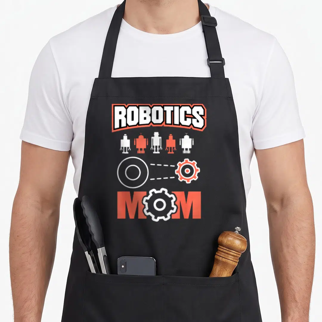 Robotic coding engineer apron - ROBOTICS and MOM text with five robots and gears in orange and white — shown on a black cotton canvas apron against a white background
