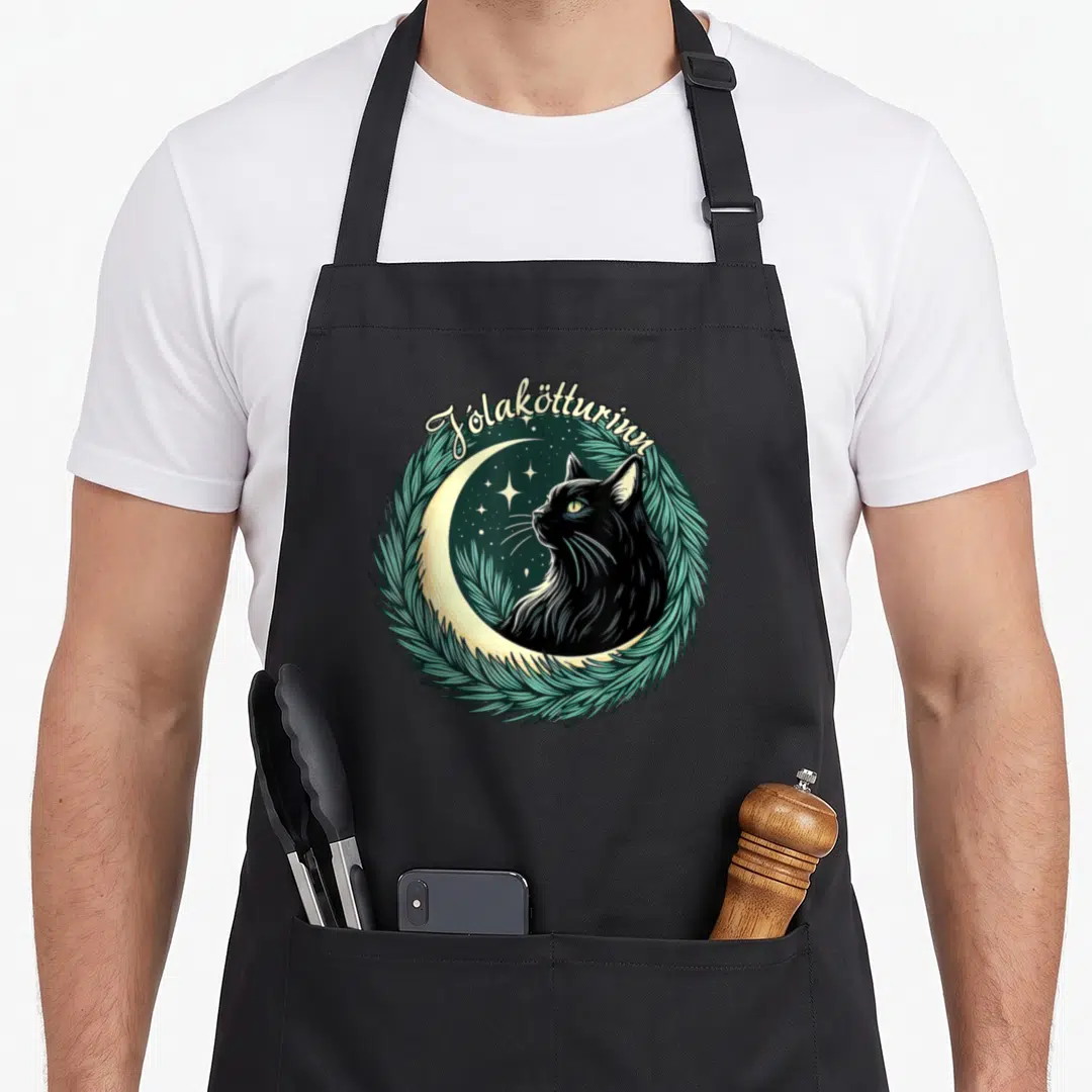 Jolakotturinn christmas cat apron - Retro black cat crescent moon pine wreath Jólakötturinn text art — shown on a black cotton canvas apron against a white background