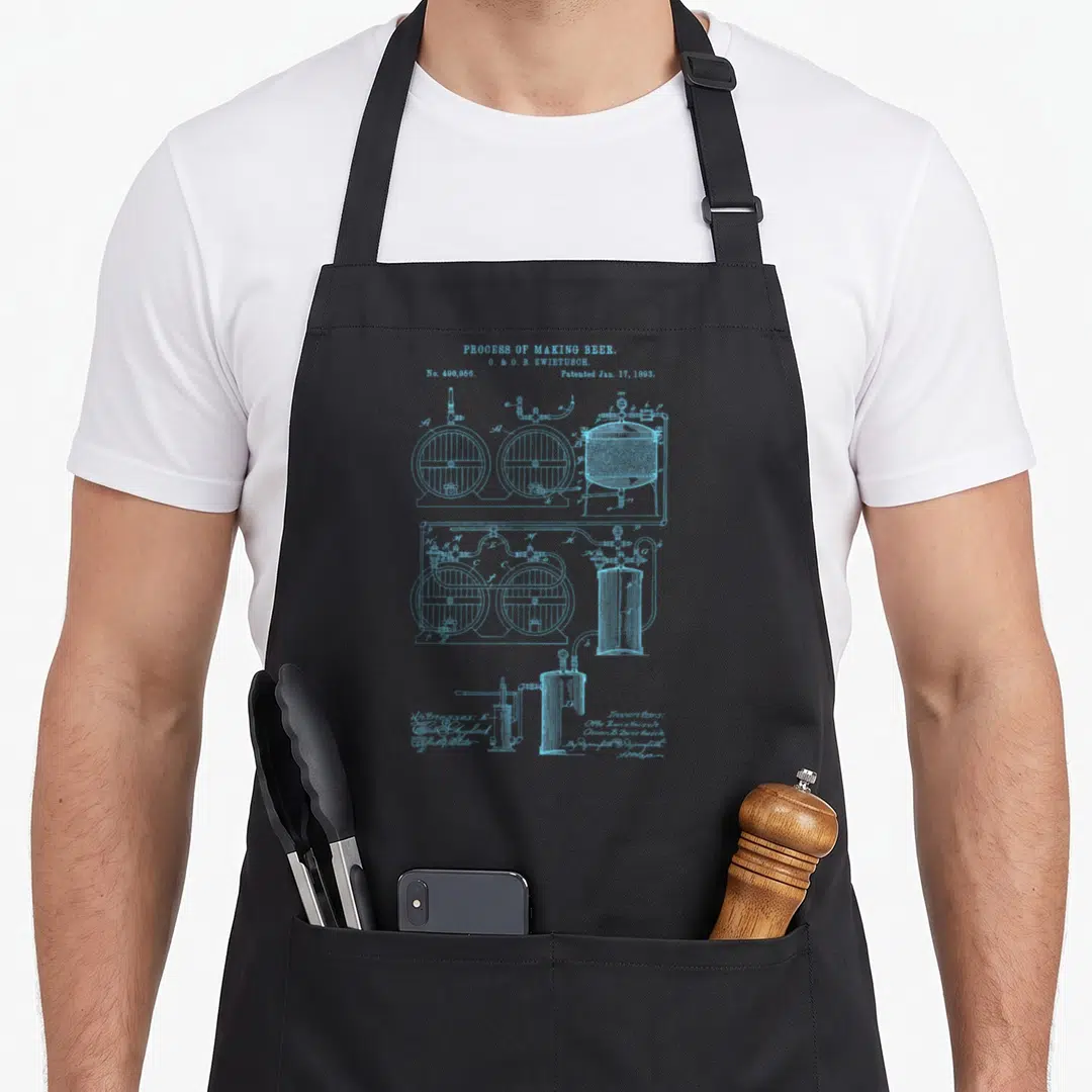 Brewery blueprint beer brewing apron - Light blue technical schematic of brewing tanks and pipes from a 1893 patent — shown on a black cotton canvas apron against a white background