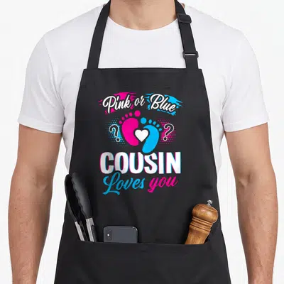 Cousin apron or apron - Pink and blue footprints with heart and text Pink or Blue Cousin Loves you — shown on a black cotton canvas apron against a white background