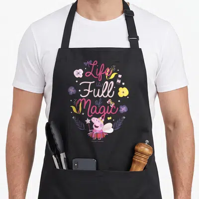 Vintage magic apron - Peppa Pig fairy with wand surrounded by pink purple yellow flowers butterflies stars — shown on a black cotton canvas apron against a white background