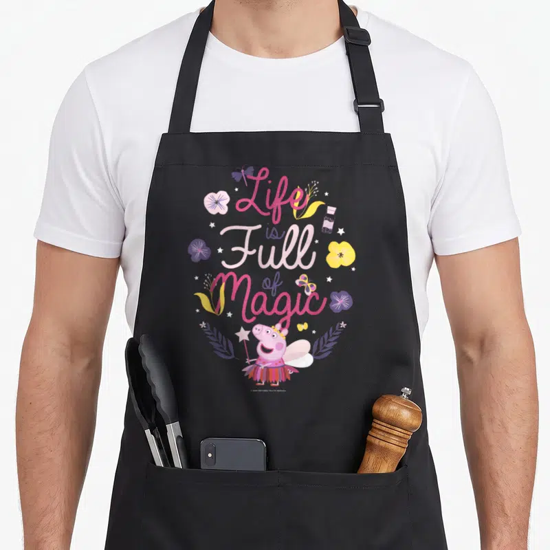 Vintage magic apron - Peppa Pig fairy with wand surrounded by pink purple yellow flowers butterflies stars — shown on a black cotton canvas apron against a white background
