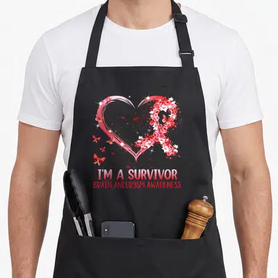 Survivor brain aneurysm awareness apron - Pink heart outline with red white rose ribbon butterflies and text I'M — shown on a black cotton canvas apron against a white background