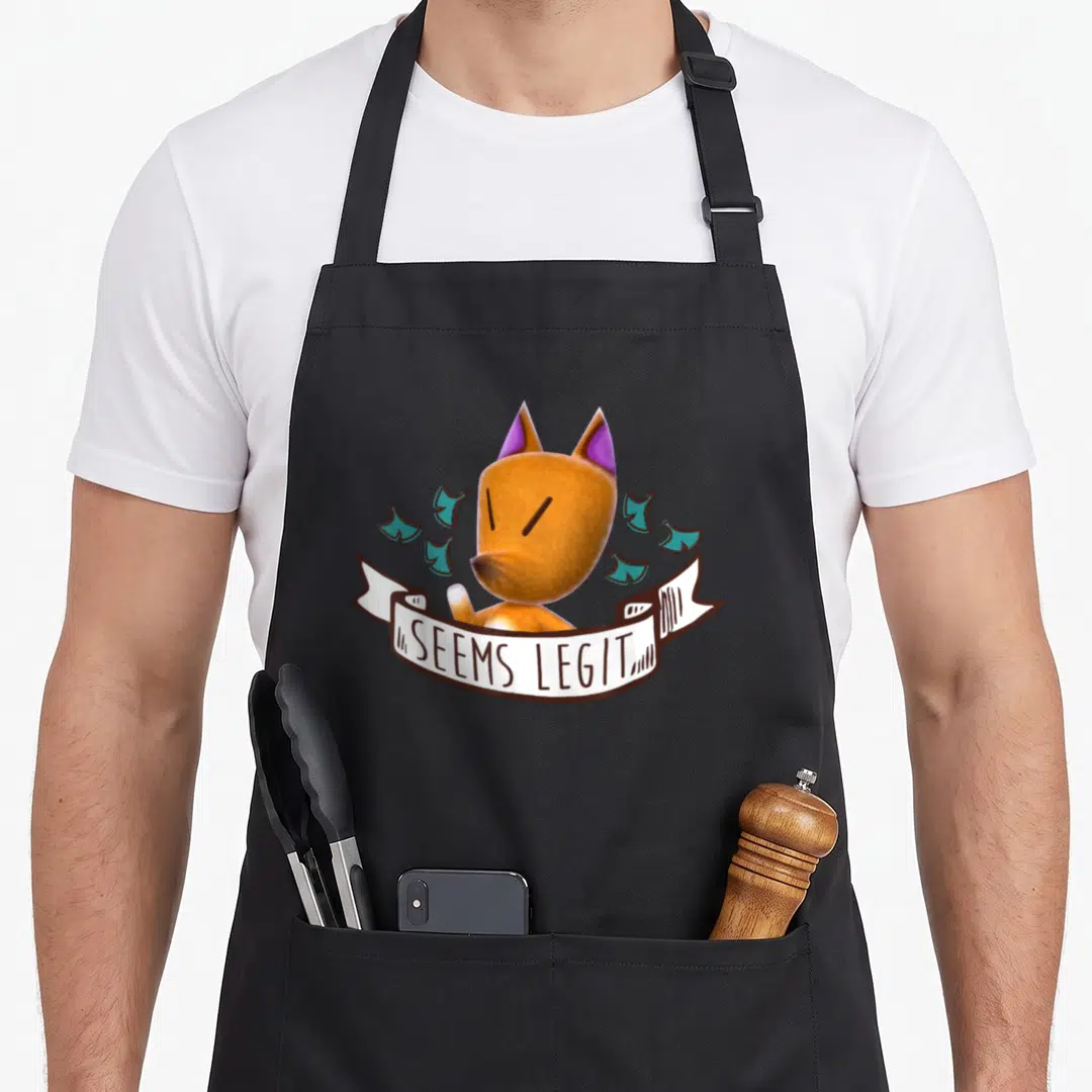 Redd animal apron - Cartoon fox head with white banner reading SEEMS LEGIT and scattered teal shapes — shown on a black cotton canvas apron against a white background