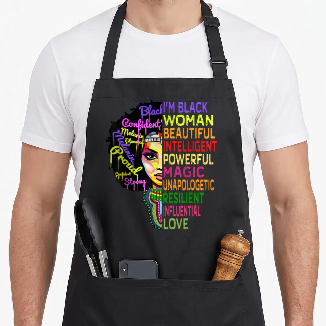 Juneteenth history african apron - Split-face woman with dripping script and stacked block words in black yellow pink — shown on a black cotton canvas apron against a white background