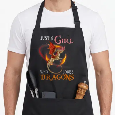 Cute dragon apron - Realistic gold dragon with red and orange fire swirl and text JUST A GIRL WHO LOVES DRAGONS — shown on a black cotton canvas apron against a white background
