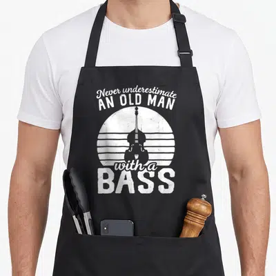 String double apron - White retro text Never underestimate an old man with a BASS over double bass silhouette — shown on a black cotton canvas apron against a white background