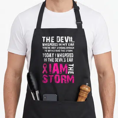 Storm breast cancer awareness aprons - Distressed white and pink text reading I Am The Storm with pink ribbon symbol — shown on a black cotton canvas apron against a white background