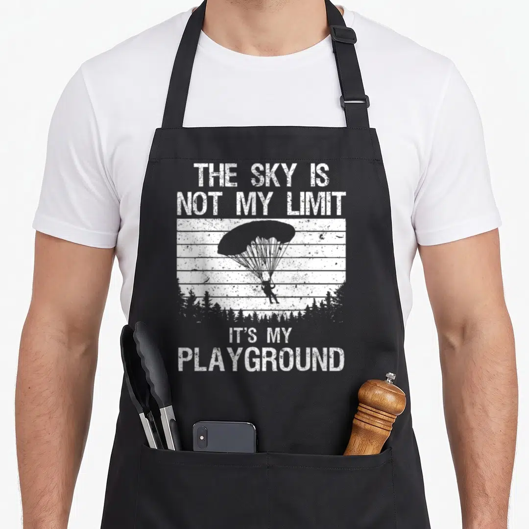 Skydive skydiver skydiving apron - Distressed parachutist descending over trees with horizontal stripes and text — shown on a black cotton canvas apron against a white background