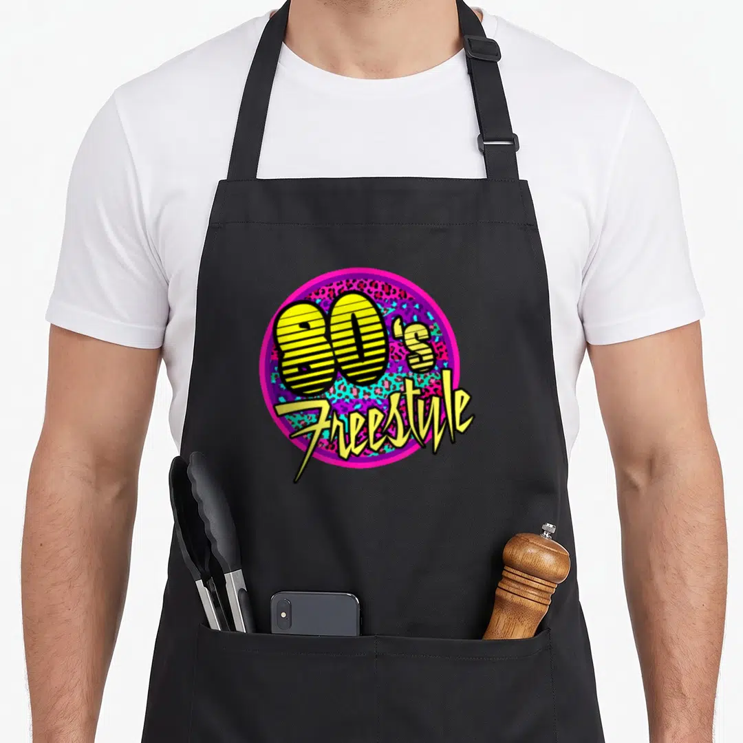 Dance 80s apron - 80's Freestyle text in striped yellow font inside pink circle with leopard print background — shown on a black cotton canvas apron against a white background