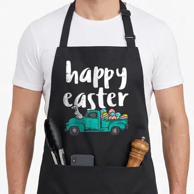 Pickup easter bunny aprons - Teal truck with white bunny and colorful eggs under stacked happy easter text — shown on a black cotton canvas apron against a white background