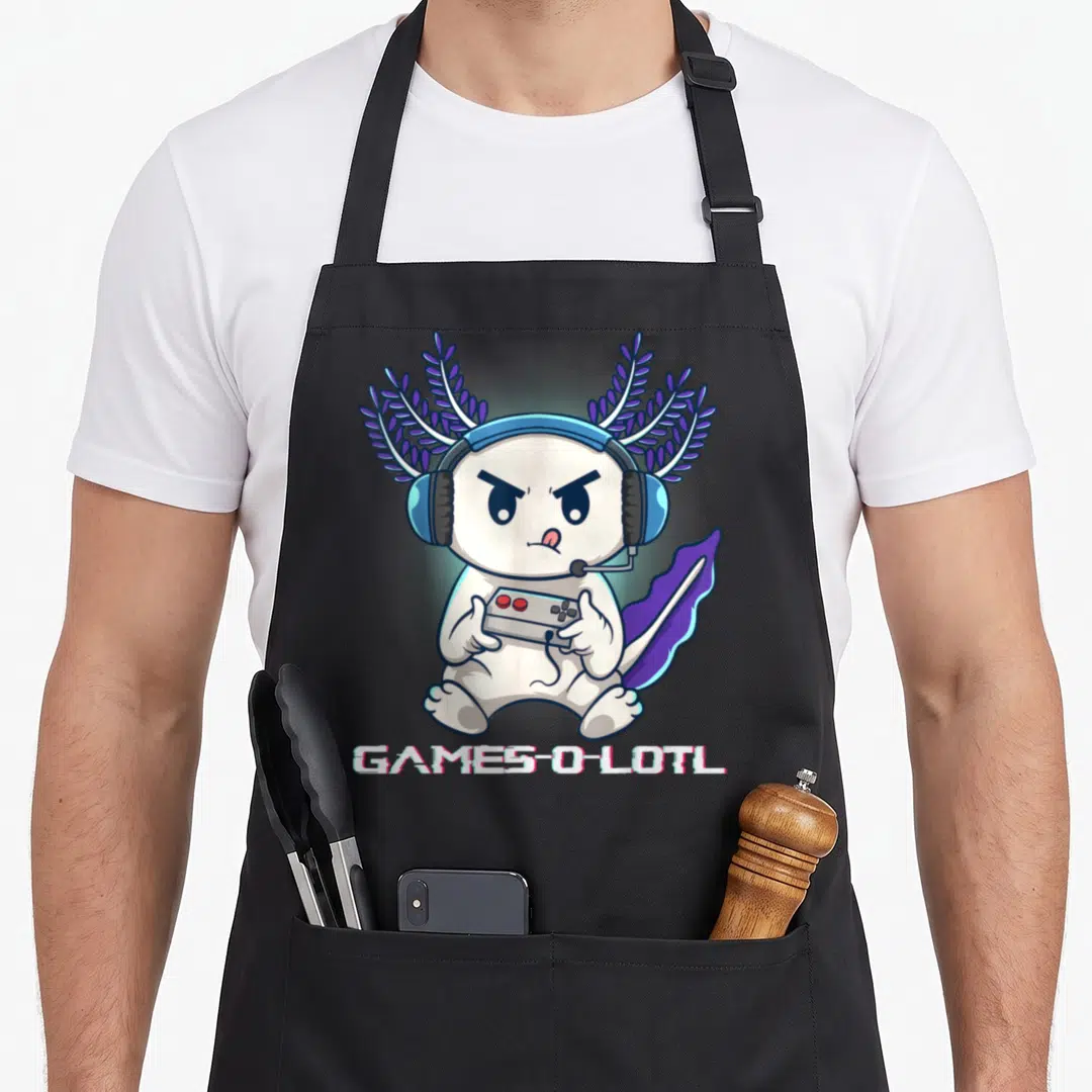 Axolotl video game apron - White cartoon axolotl with purple gills holding controller under GAMES-O-LOTL text — shown on a black cotton canvas apron against a white background