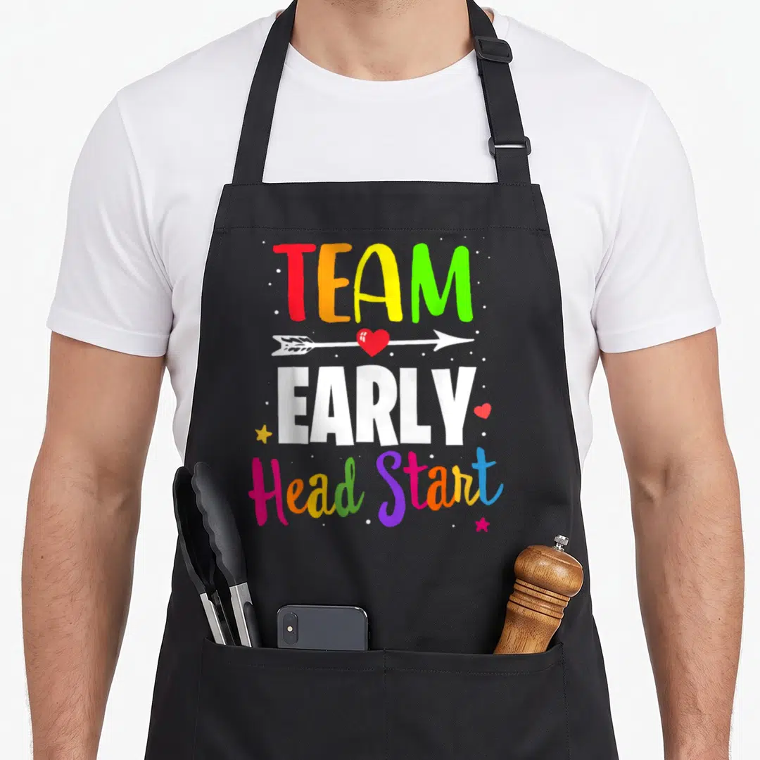 Early childhood preschool teacher apron - Stacked colorful text Team Early Head Start with red heart arrow and white — shown on a black cotton canvas apron against a white background