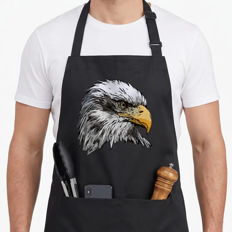 National eagles apron - Line art bald eagle head in white, yellow, and black on black fabric — shown on a black cotton canvas apron against a white background