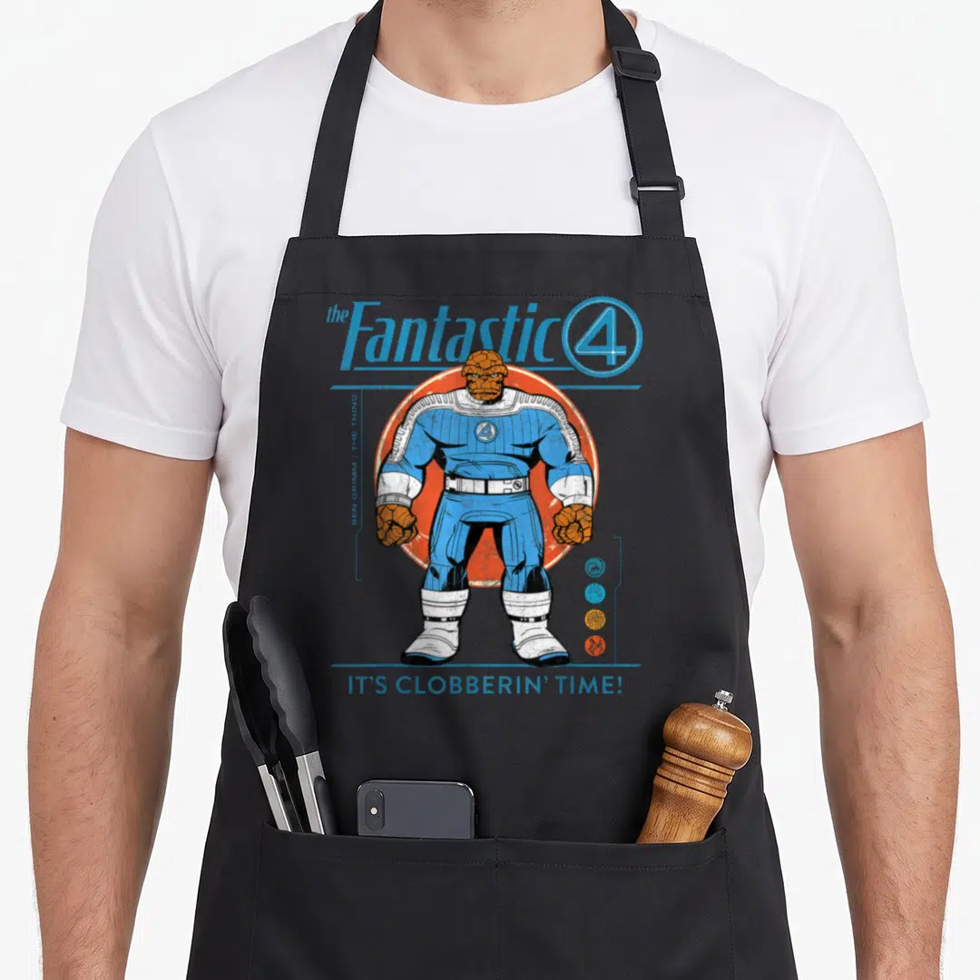 Funny fantastic first steps apron - The Thing Ben Grimm blue suit orange circle clobberin time text retro cartoon — shown on a black cotton canvas apron against a white background