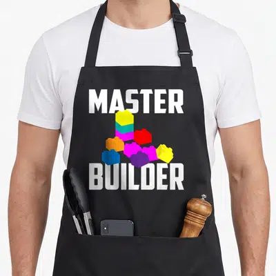 Builder brick block & apron - Master Builder text surrounding yellow magenta blue red and orange toy blocks — shown on a black cotton canvas apron against a white background