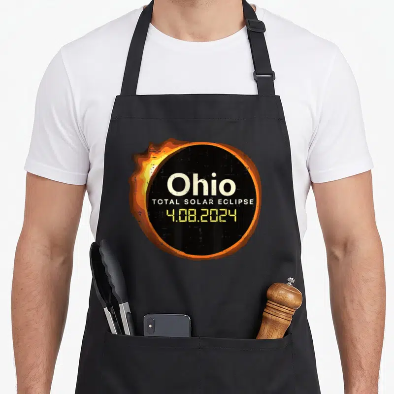 Ohio april apron - Retro black circle with orange corona and stacked text reading Ohio Total Solar Eclipse 4.08.2024 — shown on a black cotton canvas apron against a white background