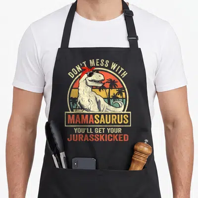 Mess mother's day aprons - Dinosaur in sunglasses with red bandana and retro sunset text — shown on a black cotton canvas apron against a white background