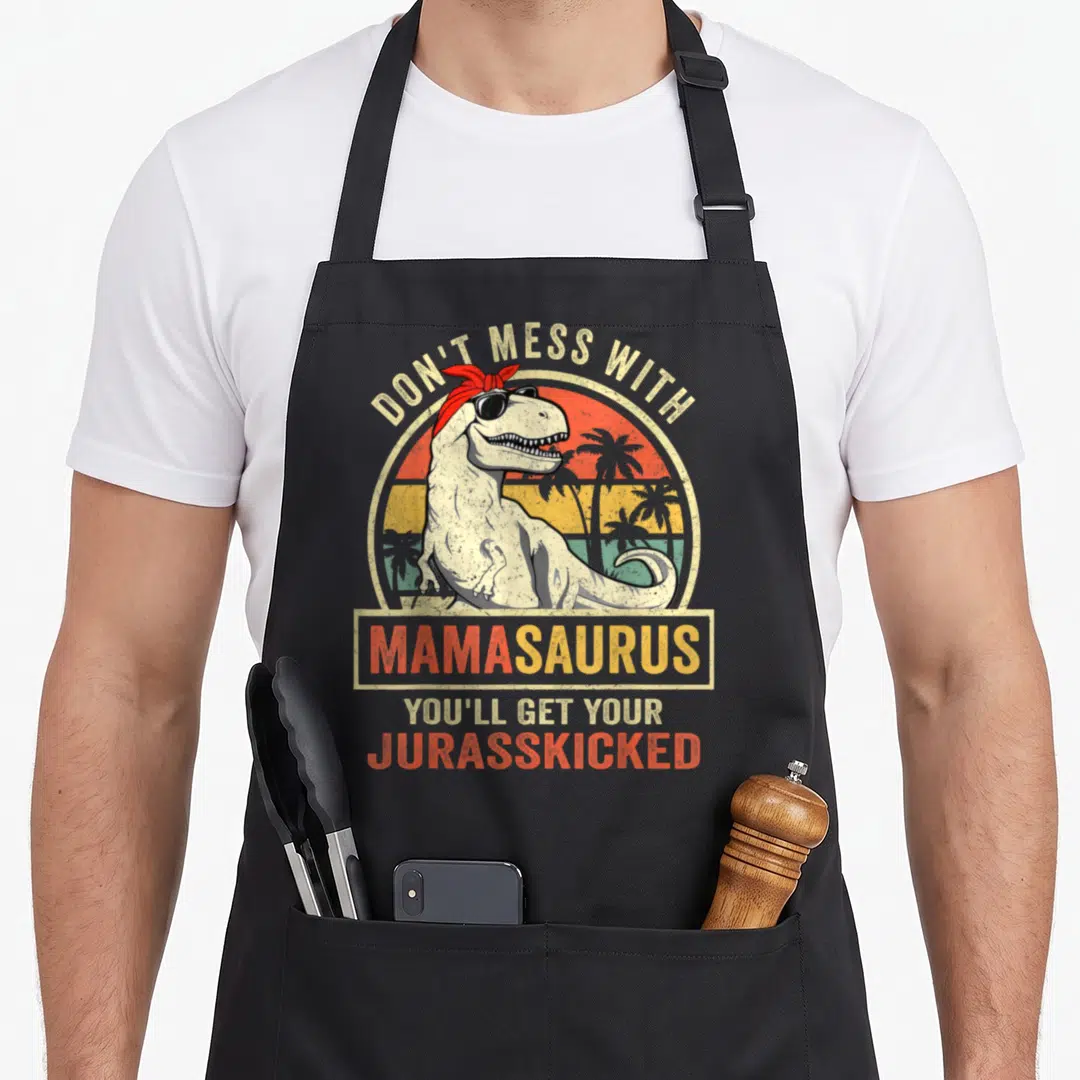 Mess mother's day aprons - Dinosaur in sunglasses with red bandana and retro sunset text — shown on a black cotton canvas apron against a white background