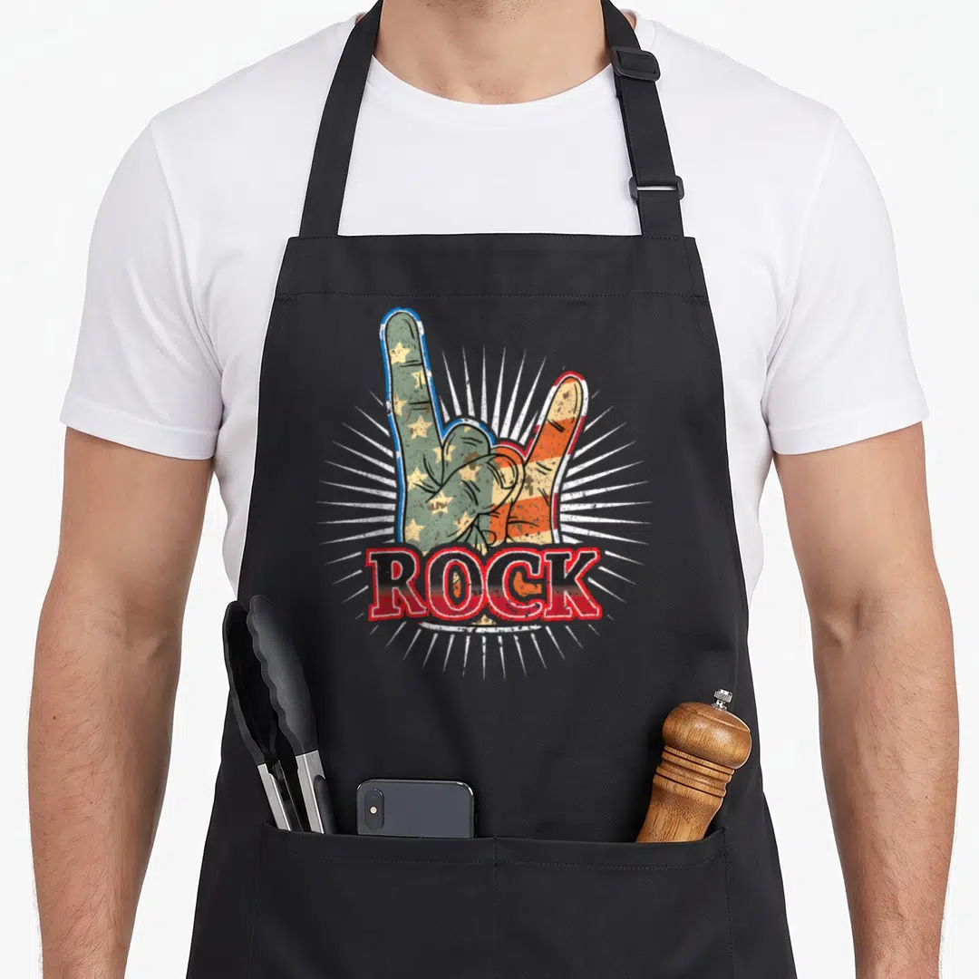 Rock 70s apron - Hand making rock sign filled with red white blue flag pattern and distressed ROCK text — shown on a black cotton canvas apron against a white background