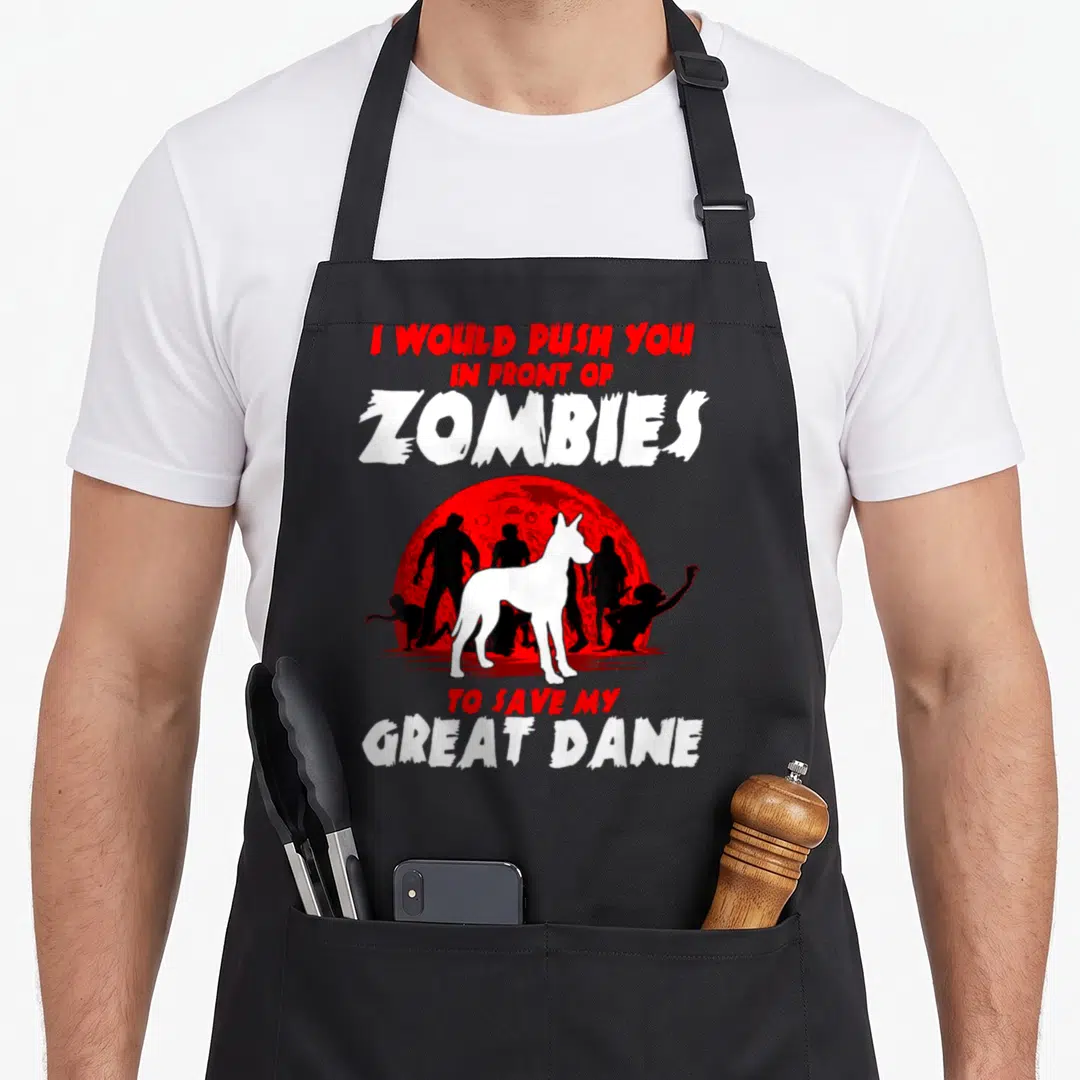 Zombie dog apron - Great Dane silhouette in front of red moon and black zombies with protective text — shown on a black cotton canvas apron against a white background