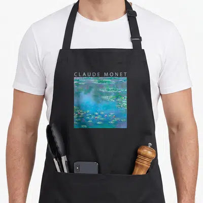 Impressionism white lily apron - CLAUDE MONET text above blue green purple pink water lily watercolor painting — shown on a black cotton canvas apron against a white background