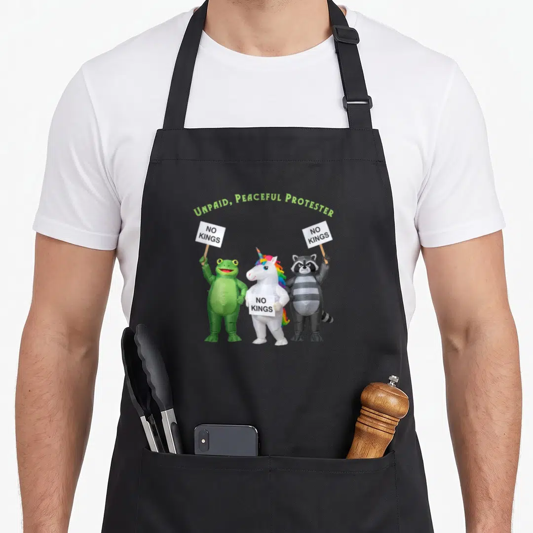Unpaid king apron - Three inflatable frogs unicorns raccoons holding NO KINGS signs under green text — shown on a black cotton canvas apron against a white background