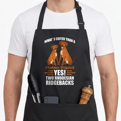 Rhodesian ridgeback apron for women - Two sitting brown and white Rhodesian Ridgeback dogs with stacked humorous text — shown on a black cotton canvas apron against a white background