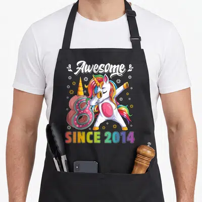 Dabbing unicorn 8th birthday apron - Cartoon unicorn dabbing next to pink number 8 with since 2014 rainbow text — shown on a black cotton canvas apron against a white background