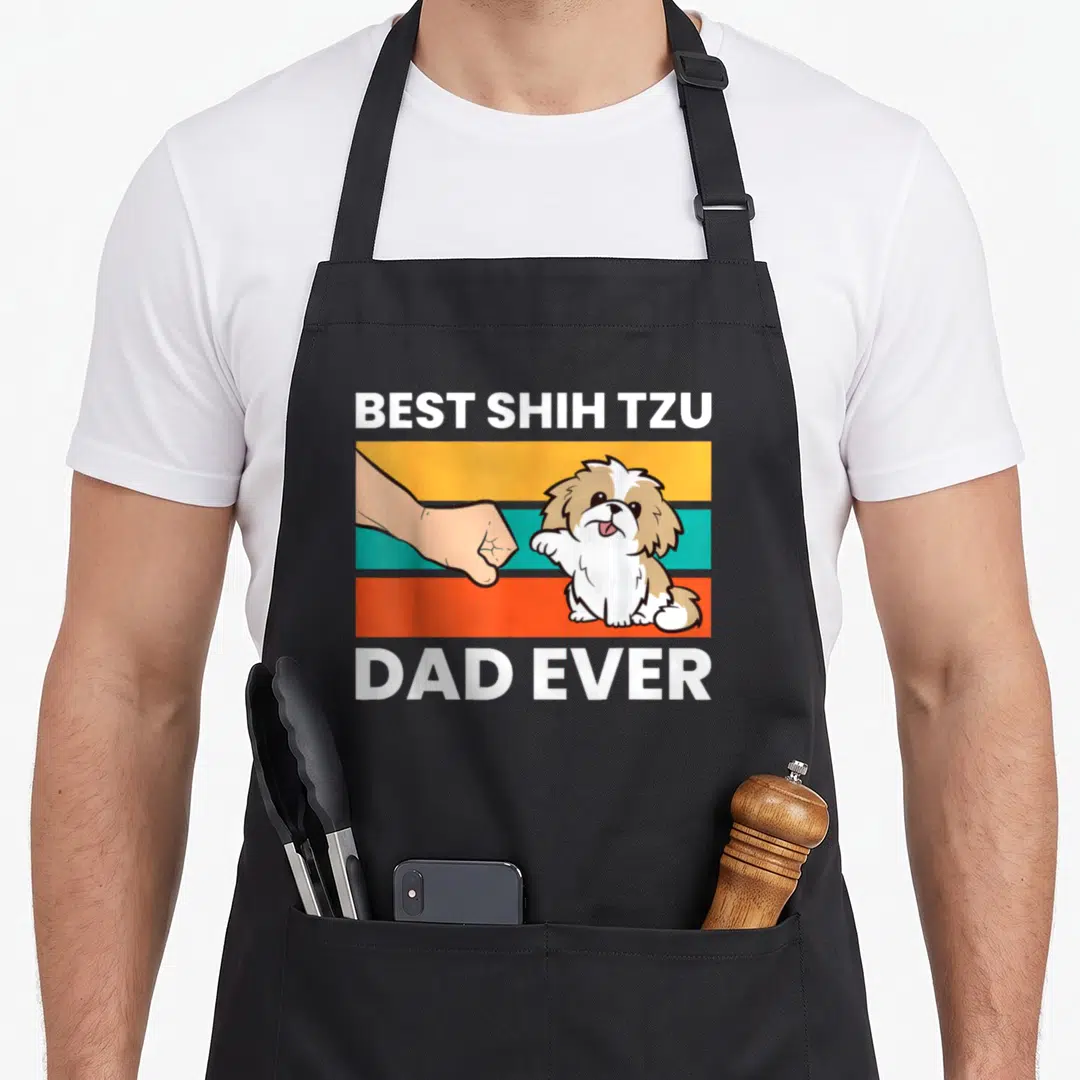 Funny shih tzu apron - Cartoon shih tzu fist bumping a human hand over three colored stripes with best shih tzu dad — shown on a black cotton canvas apron against a white background