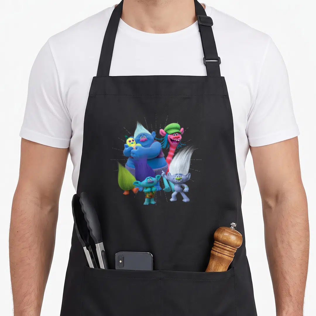 Funny troll apron - Four cartoon trolls in blue, pink, purple, and yellow clustered together holding a toy — shown on a black cotton canvas apron against a white background
