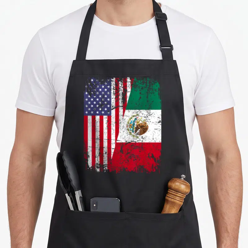 Mexican american flag apron - Two flags merged diagonally in distressed red white blue and green with eagle emblem — shown on a black cotton canvas apron against a white background