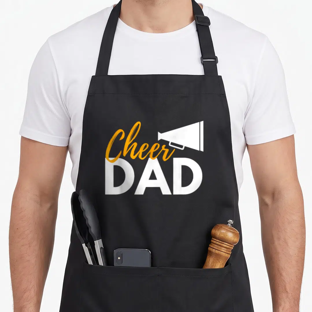 Cheer cheerleader cheerleading apron - Orange script Cheer and white DAD text with a white megaphone icon — shown on a black cotton canvas apron against a white background