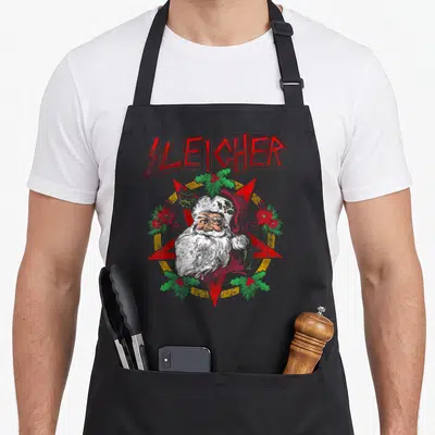 Santa heavy metal apron - SLEICHER text above Santa head inside red pentagram with holly and berries — shown on a black cotton canvas apron against a white background