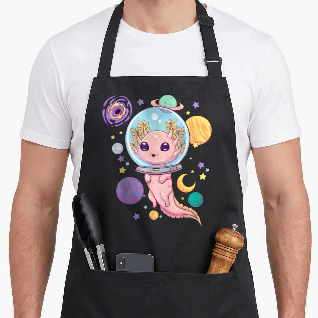 Axolotl anime cooking apron - Pink axolotl in space helmet surrounded by planets and stars in cartoon style — shown on a black cotton canvas apron against a white background