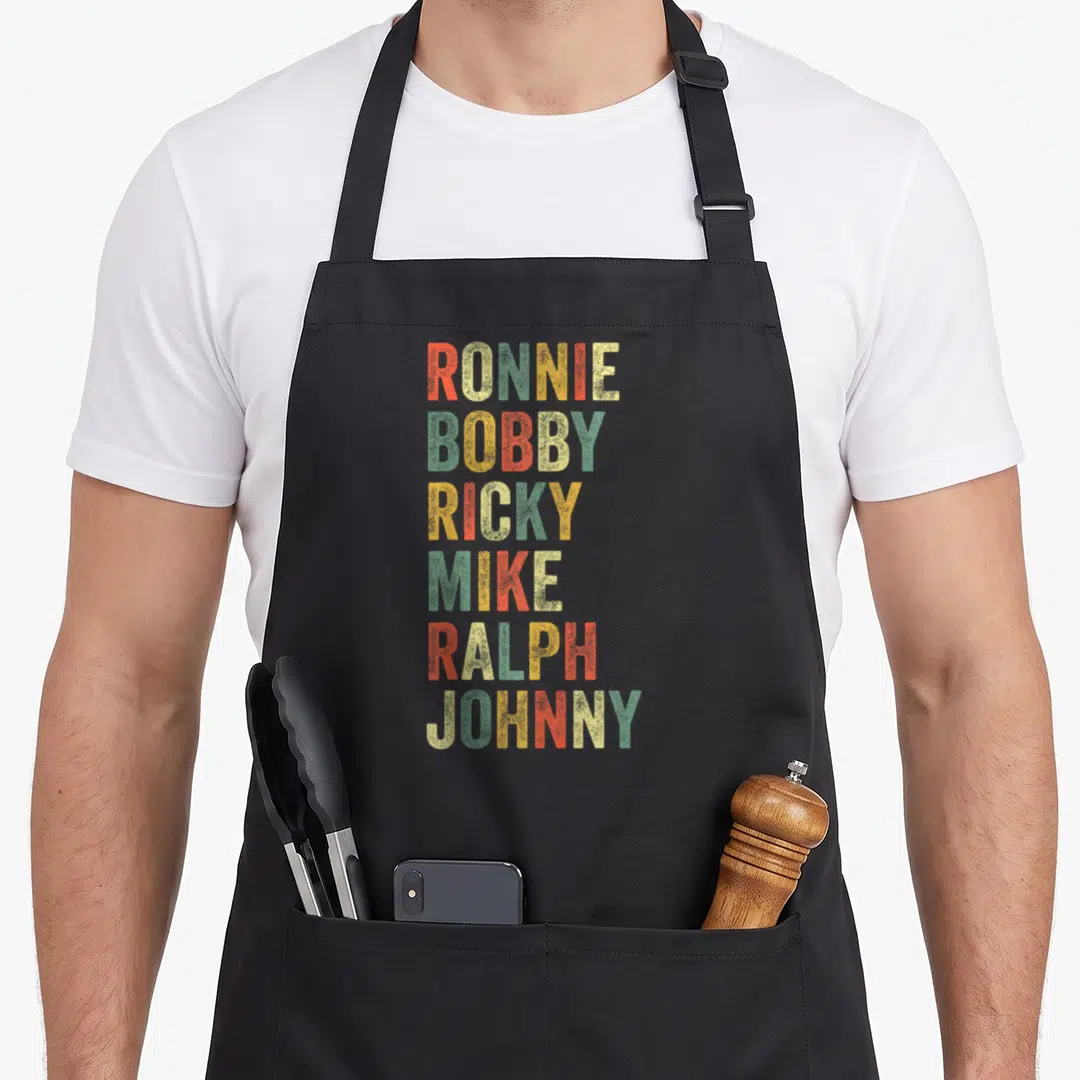 Ronnie hip aprons - Six stacked names Ronnie Bobby Ricky Mike Ralph Johnny in orange green yellow red distressed font — shown on a black cotton canvas apron against a white background