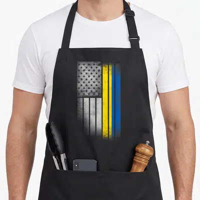 Funny ukrainian american flag apron - Vertical distressed flag design with grey stars and yellow blue stripes — shown on a black cotton canvas apron against a white background