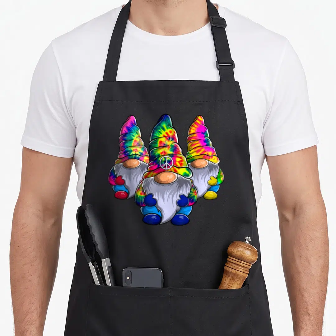 Three hippie apron - Three tie-dye gnomes with white peace sign on center hat — shown on a black cotton canvas apron against a white background
