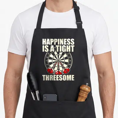 Happiness darts apron - Dartboard with three red darts and distressed text reading HAPPINESS IS A TIGHT THREESOME — shown on a black cotton canvas apron against a white background