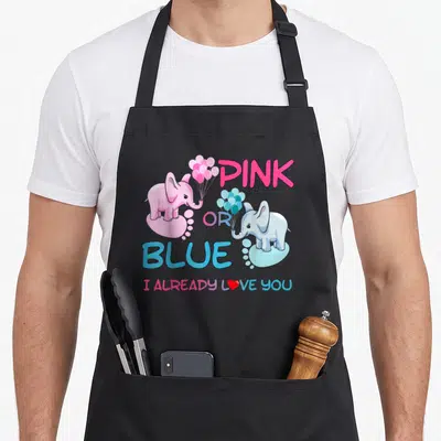 Gender family aprons - Pink and blue elephants holding balloons with stacked PINK OR BLUE text and I ALREADY LOVE YOU — shown on a black cotton canvas apron against a white background