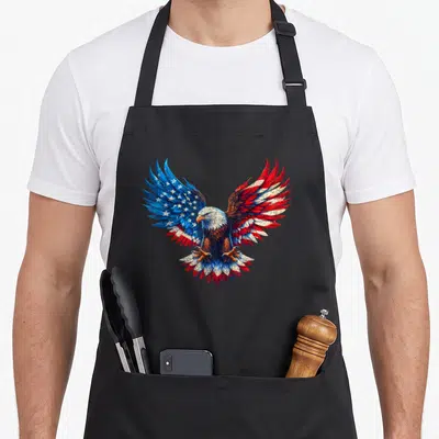 Flag bald 4th of july apron - Realistic eagle with spread wings filled with red white and blue flag pattern — shown on a black cotton canvas apron against a white background