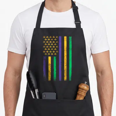 Flag mardi gras aprons - Distressed flag with purple yellow green stripes and fleur de lis grid pattern — shown on a black cotton canvas apron against a white background