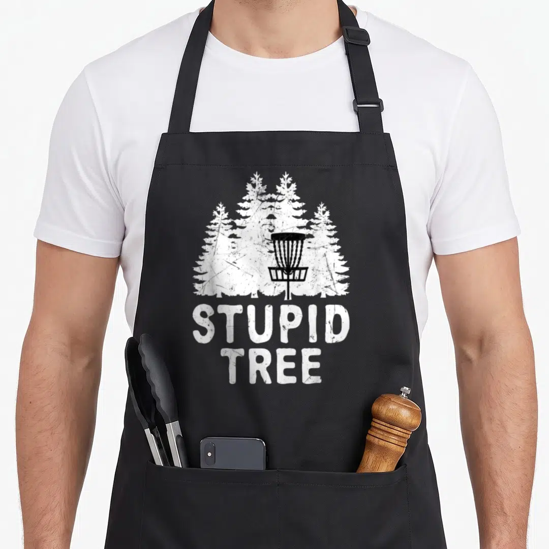Disc stupid golf apron - Black disc golf basket over white distressed pine trees with text STUPID TREE — shown on a black cotton canvas apron against a white background