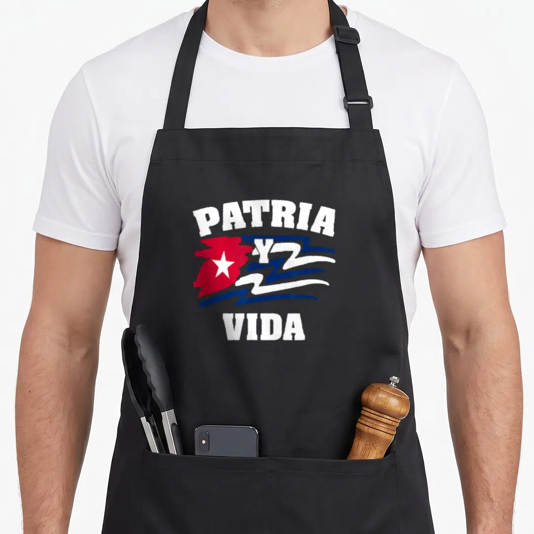 Vida cuban boy apron - PATRIA Y VIDA text surrounding stylized brush-stroke Cuban flag with star in white red and blue — shown on a black cotton canvas apron against a white background