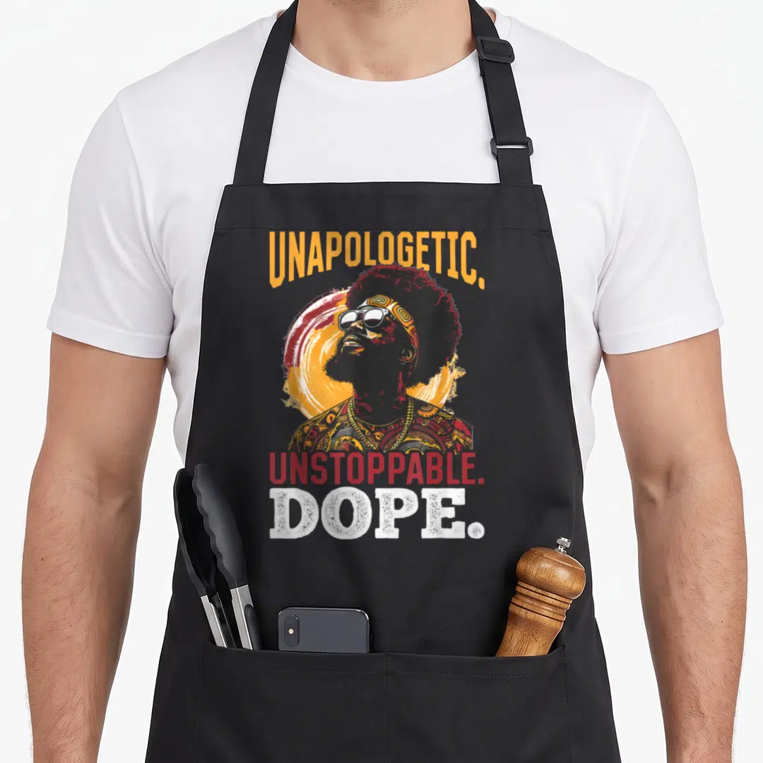 Unstoppable unapologetic apron - Retro man with sunglasses and arched UNAPOLOGETIC. UNSTOPPABLE. DOPE. text in orange — shown on a black cotton canvas apron against a white background