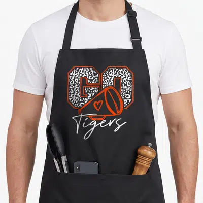 Cheer football apron - leopard-print GO letters, orange megaphone with heart, white Tigers script — shown on a black cotton canvas apron against a white background