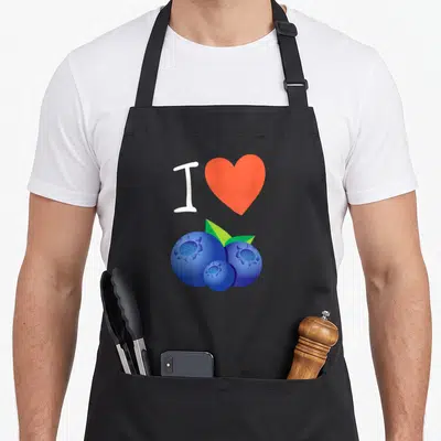 Blueberry christmas apron - White I and orange heart above three blueberries with green leaves — shown on a black cotton canvas apron against a white background