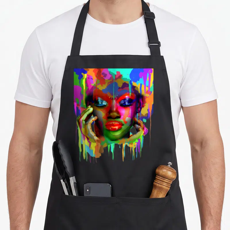Afro african apron - Watercolor woman's face framed by hands with blue red yellow green and pink paint drips — shown on a black cotton canvas apron against a white background