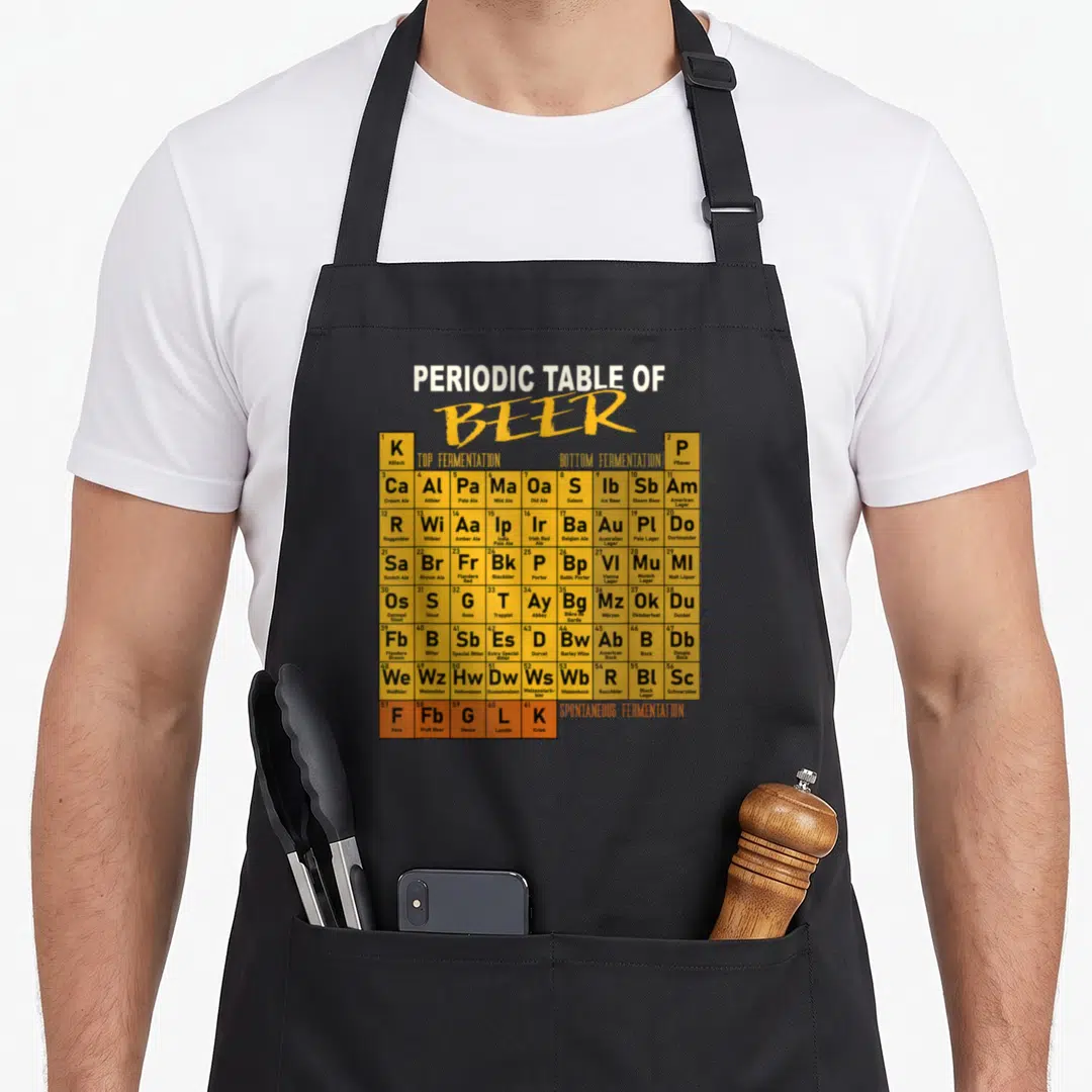 Beer table apron - Periodic table of beer chart with yellow fermentation cells and black text listing styles like — shown on a black cotton canvas apron against a white background